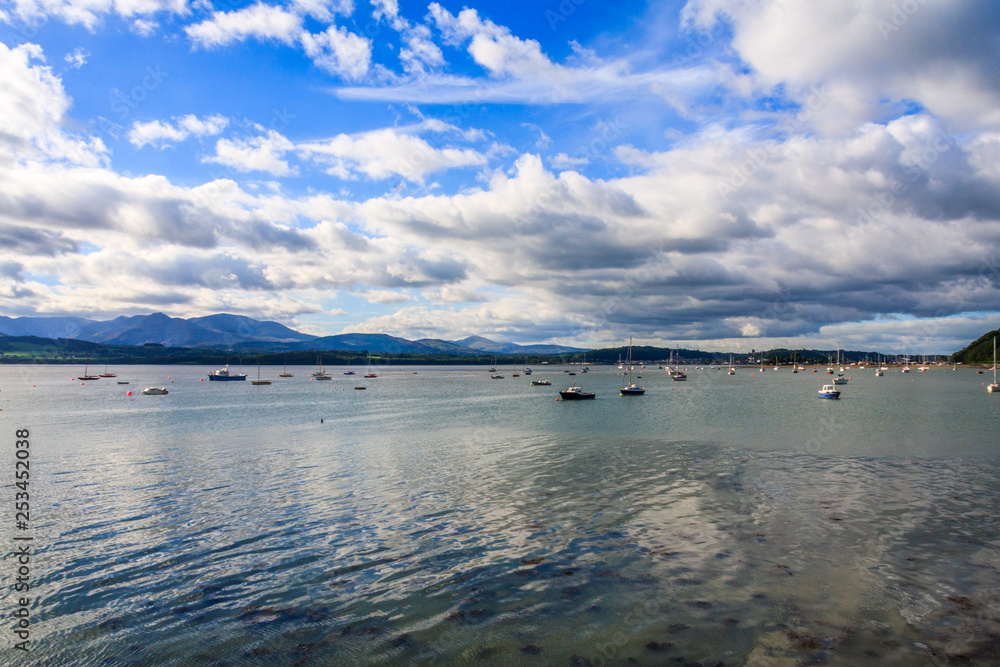 Blue sky and clouds over boats moored in the Menai Straits. Taken from Beaumaris, Anglesey, Wales, UK