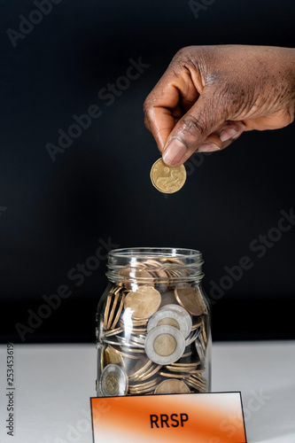 African American Nigerian woman dropping coins into RRSP jar photo