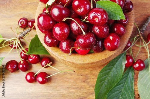 Sweet cherry fruits with leaves in a wooden bowl