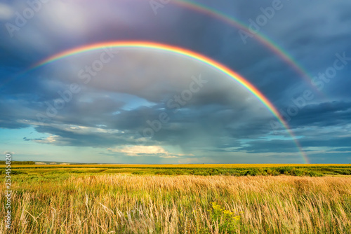Rainbow over stormy sky. Rural landscape with rainbow over dark stormy sky in a countryside at summer day.