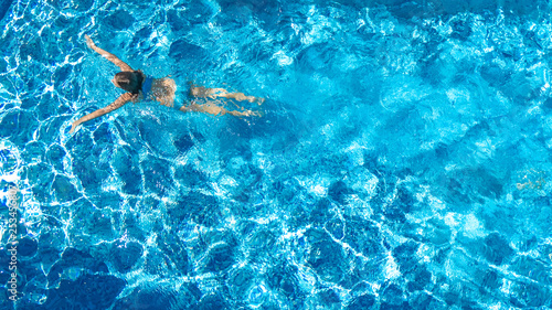 Active girl in swimming pool aerial drone view from above, young woman swims in blue water, tropical vacation, holiday on resort concept