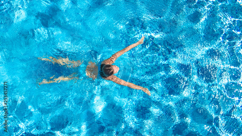 Active girl in swimming pool aerial drone view from above, young woman swims in blue water, tropical vacation, holiday on resort concept