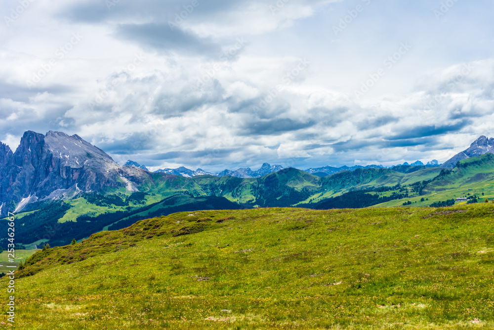 Alpe di Siusi, Seiser Alm with Sassolungo Langkofel Dolomite, a large green field with a mountain in the background Alpe di Siusi, Seiser Alm with Sassolungo Langkofel Dolomite, a large green field with a mountain in the background