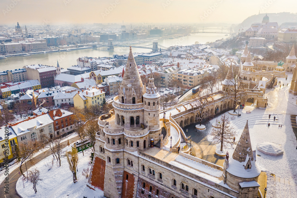 Fototapeta premium Budapest, Hungary - Aerial view of the snowy Fisherman's Bastion with Szechenyi Chain Bridge and St. Stephen's Basilica at background on a snowy winter morning