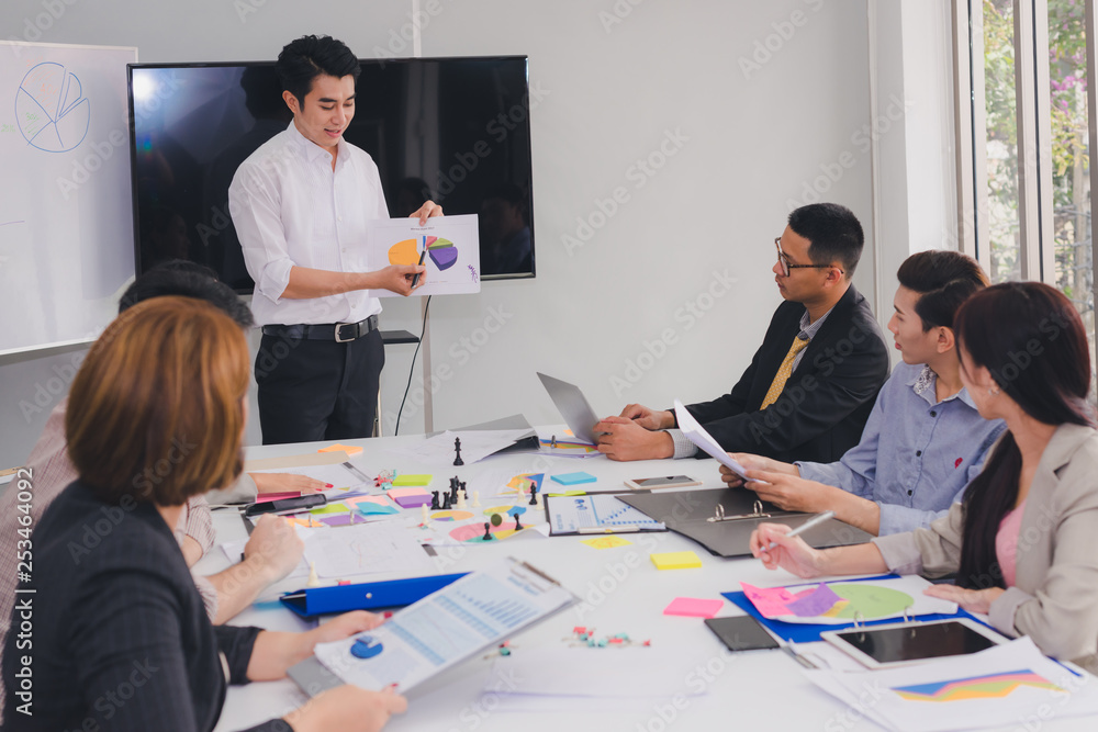 A group of Asian businessmen are discussing. Employees are presenting their work to the meeting.