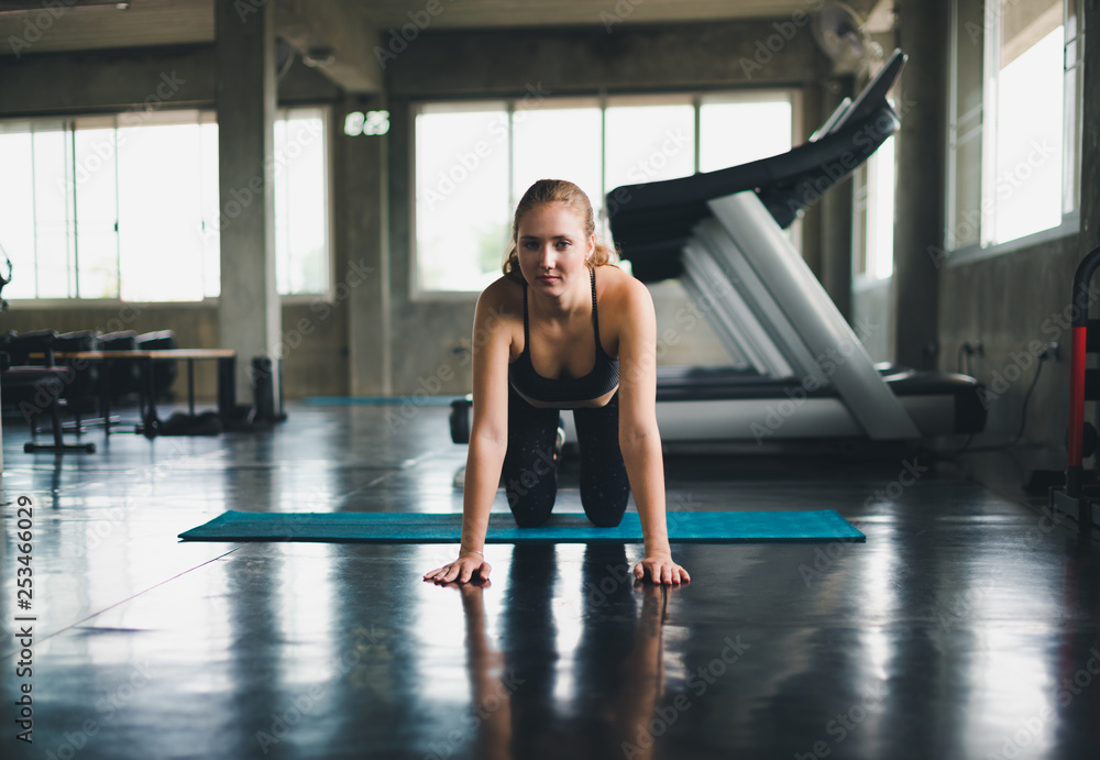 Beautiful athlete put on a sports suit. Stretching a muscle on a yoga mat. Before playing sports in the gym. She is relaxing Beautiful athlete put on a sports suit. Stretching a muscle on a yoga mat. Before playing sports in the gym. She is relaxing