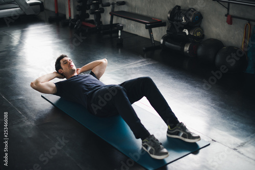 Young man caucasian Being exercised by a sit-up on yoga mat. He wears sportswear. Fitness in the gym concept.
