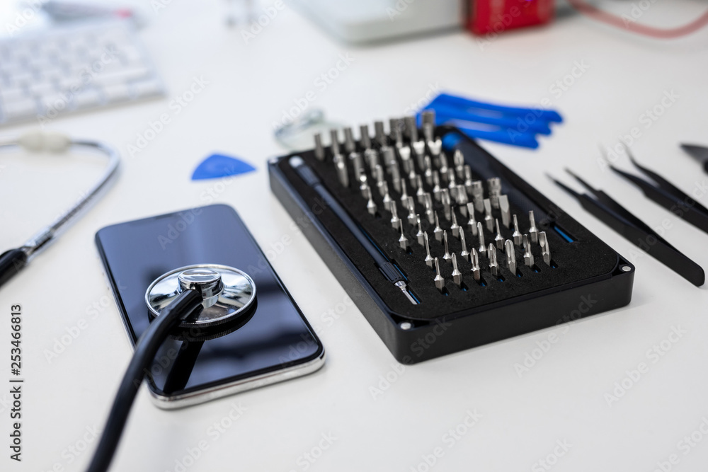 stethoscope lying on smart phone next to black tool box in repair service stethoscope lying on smart phone next to black tool box in repair service