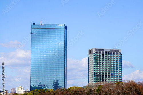 Closeup scenery view of glass and office building on blue sky background. Glass building is generally popular because it's helping to lights and reduce energy of air conditioner in the building.