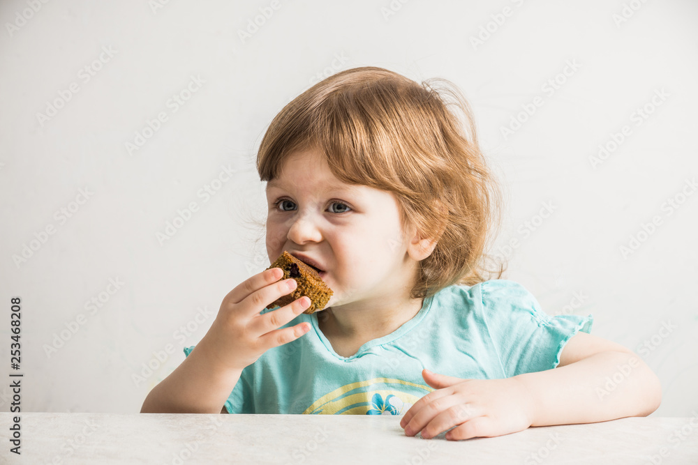 Little girl eating muffins at kitchen after help with making them. Selective focus. Little girl eating muffins at kitchen after help with making them. Selective focus.