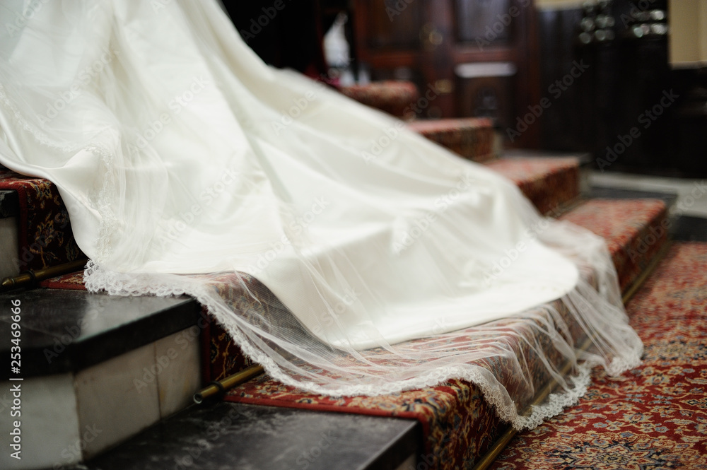 Cola de vestido de novia blanco sobre alfombra roja con estampado en escalera de altar Cola de vestido de novia blanco sobre alfombra roja con estampado en escalera de altar