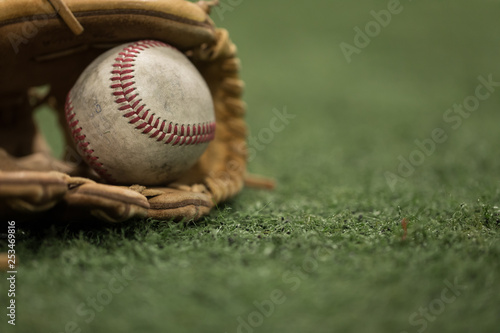 Baseball glove holding baseball on artificial grass