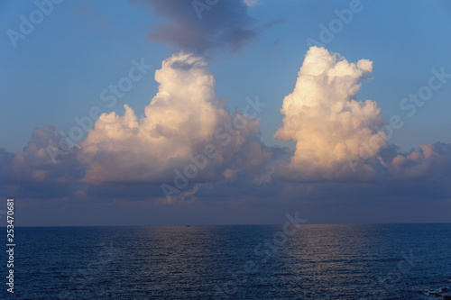 beautiful blue sky with two large white cumulus clouds over the serene surface of the Mediterranean