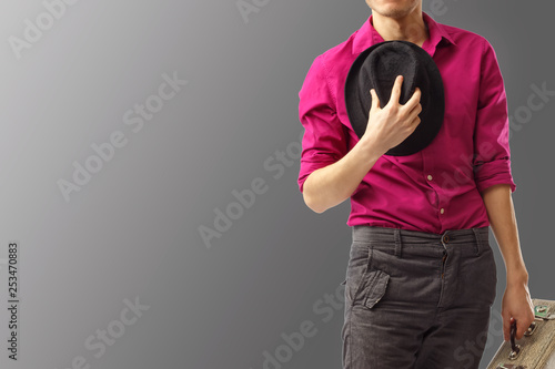 Obraz na plátne Young trendy dressed gentleman took off his hat and pressed it to his chest in greeting, declaring his openness to communication
