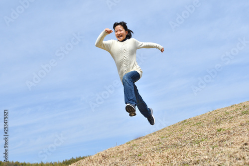 Japanese girl jumping in the blue sky