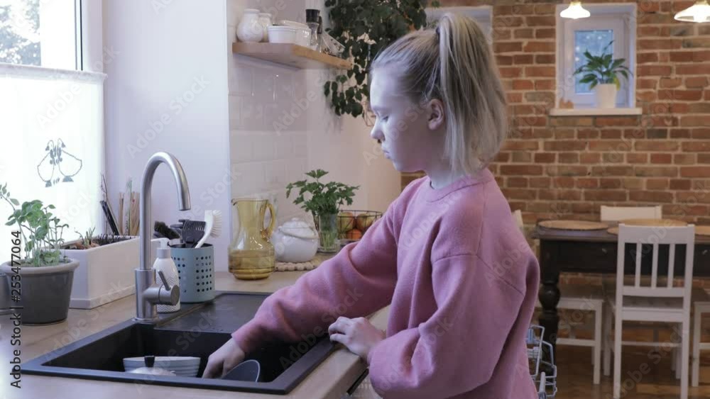 girl using dishwasher in the kitchen. girl using dishwasher in the kitchen.