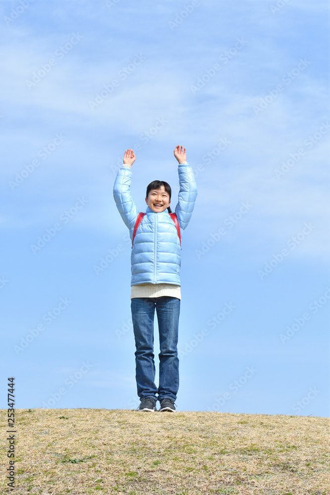 Japanese elementary school girl raising her both hands in the blue sky Japanese elementary school girl raising her both hands in the blue sky