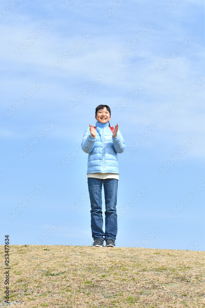 Japanese elementary school girl clapping in the blue sky