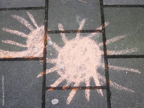 sun drawn on hte sidewalk with orange colored chalk photo