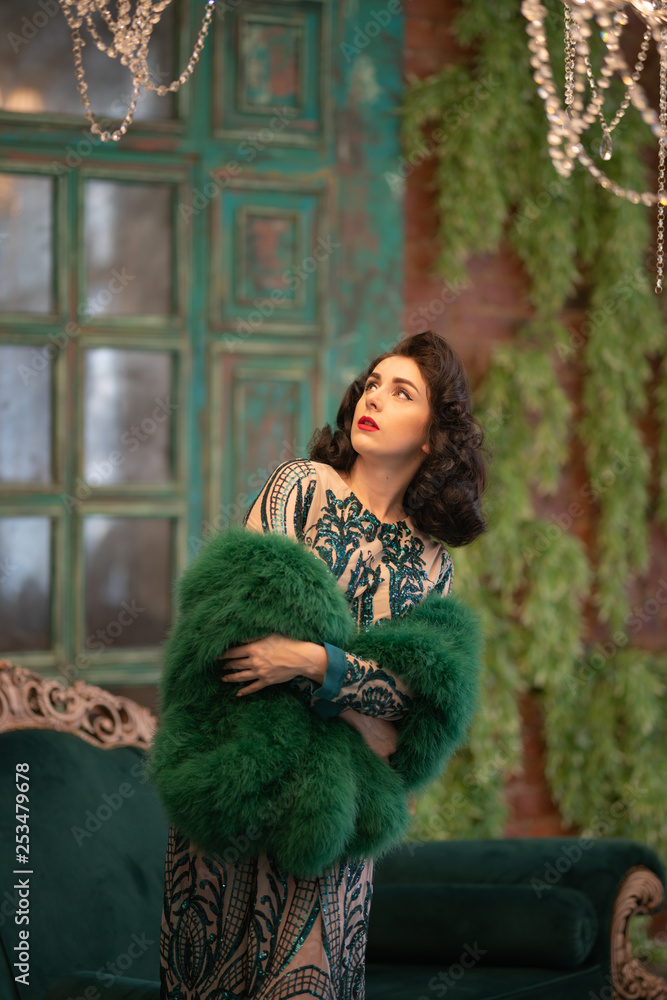 elegant caucasian girl in a luxurious long sequins lace dress with a green fluffy boa in her hands posing in the retro room with vintage luxury furniture elegant caucasian girl in a luxurious long sequins lace dress with a green fluffy boa in her hands posing in the retro room with vintage luxury furniture