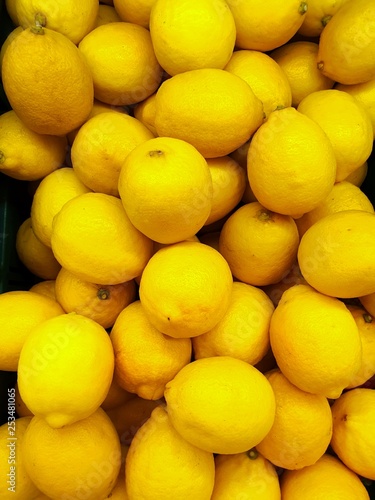 Top view of fresh lemons as a background for sale in the supermarket, for making drinks or salads, healthy food concept, Vertical