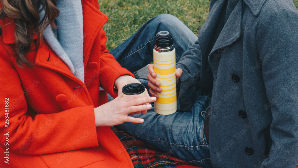 couple in love drinking coffee, tea from a thermos in the park couple in love drinking coffee, tea from a thermos in the park