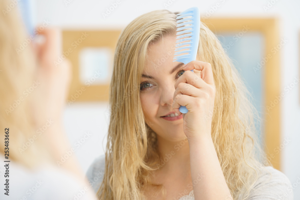 Woman brushing her wet blonde hair Woman brushing her wet blonde hair