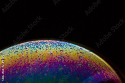 A bubble in rainbow colors on a black background.