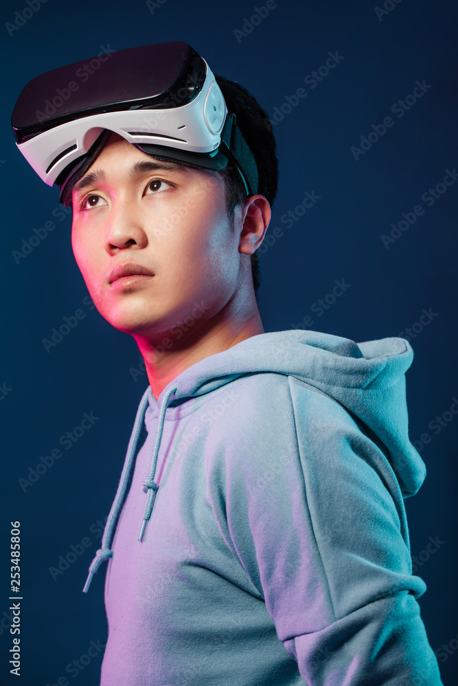 3d technology, virtual reality, gaming, entertainment and people concept - handsome young Asian male video gamer, taking off his virtual reality headset from eyes and looking aside into space. Poster 3d technology, virtual reality, gaming, entertainment and people concept - handsome young Asian male video gamer, taking off his virtual reality headset from eyes and looking aside into space. Poster