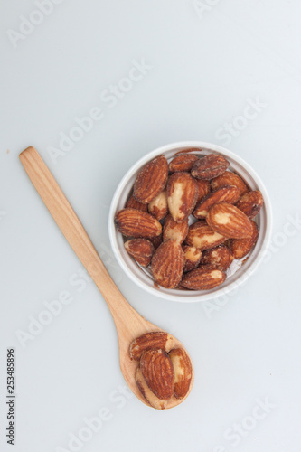 Almonds in the white small cup and wood spoon on white background, Isolate snack 