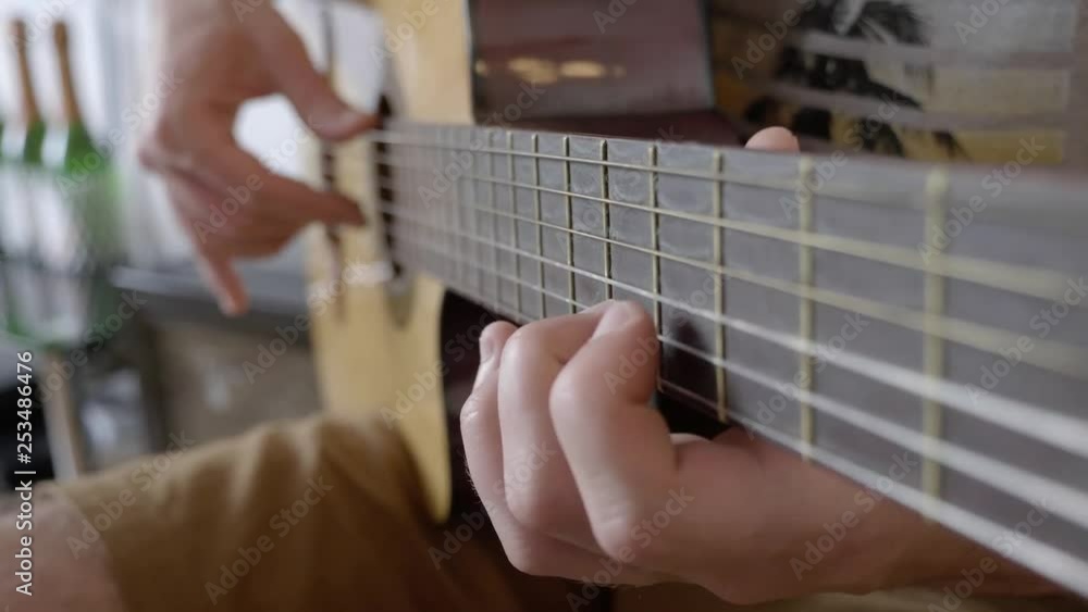 Close up on person playing strings on guitar. Sitting scene indoors at home. Close up on person playing strings on guitar. Sitting scene indoors at home.