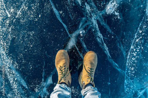 Men's yellow shoes on the pure blue ice of lake Baikal. Concept tourism and travel to famous places of nature