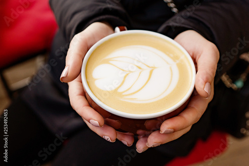 cup of coffee cappuccino in girl's hands on a dark background, macro