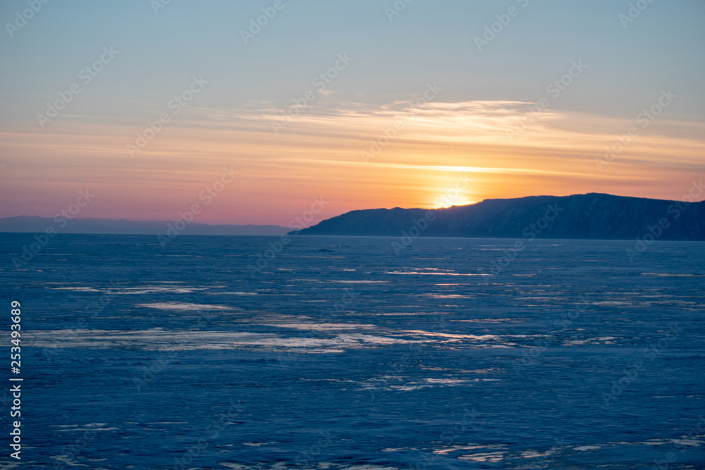 Beautiful view of the sunset landscape on the snowy lake Baikal in winter