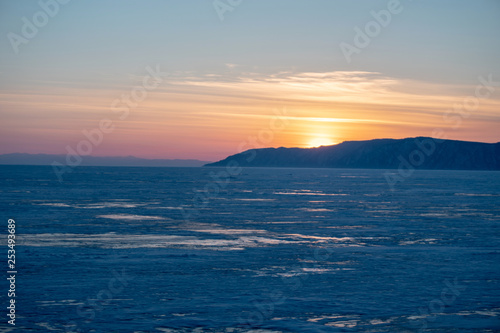 Beautiful view of the sunset landscape on the snowy lake Baikal in winter