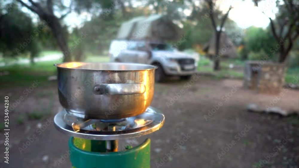 Slomo of a Steaming Cooking Pan, on a African Campsite, with a Landcruiser in Background Slomo of a Steaming Cooking Pan, on a African Campsite, with a Landcruiser in Background