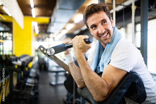 Handsome happy fit man doing exercises in gym