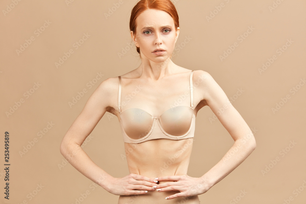 Skinny suffering female in nude underwear tied her waist with