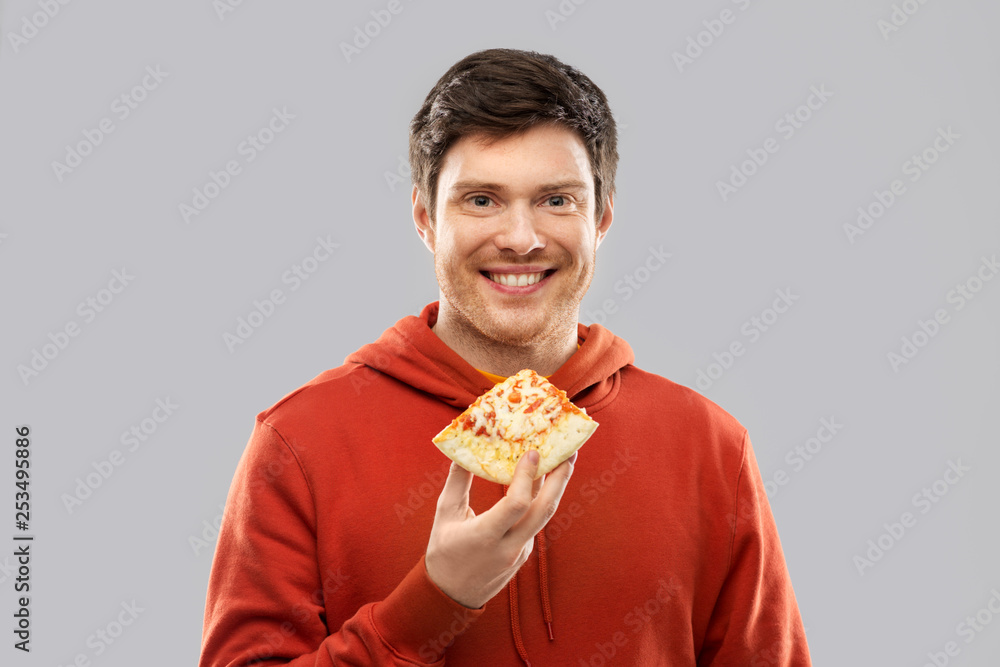 fast food and people concept - happy smiling young man in red hoodieeating pizza over grey background fast food and people concept - happy smiling young man in red hoodieeating pizza over grey background