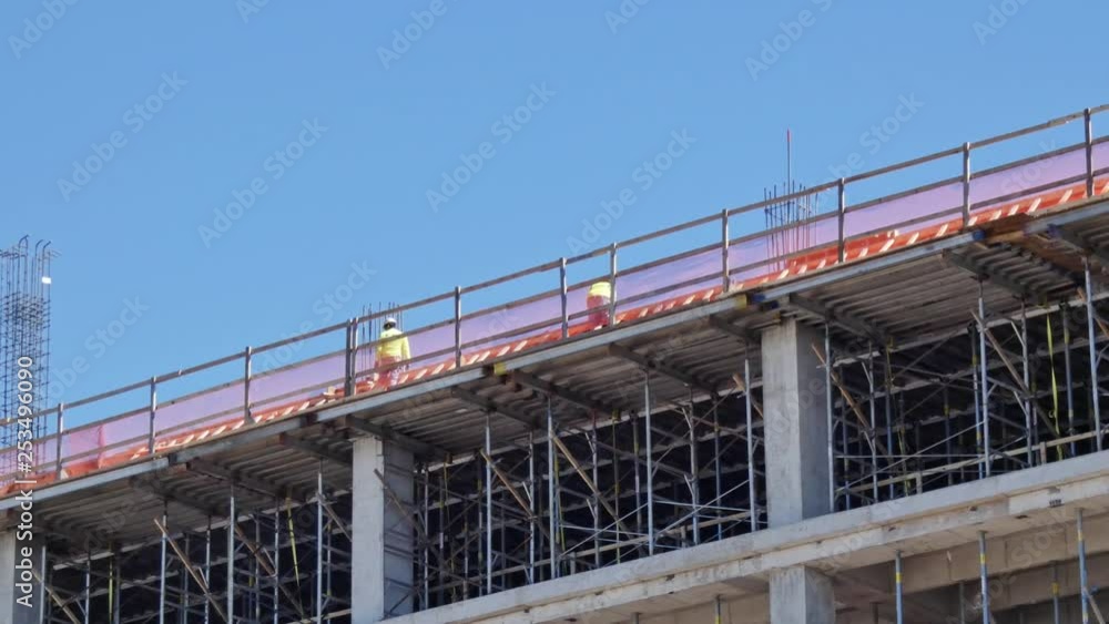 Tow men working on top of a building being built on construction site Tow men working on top of a building being built on construction site