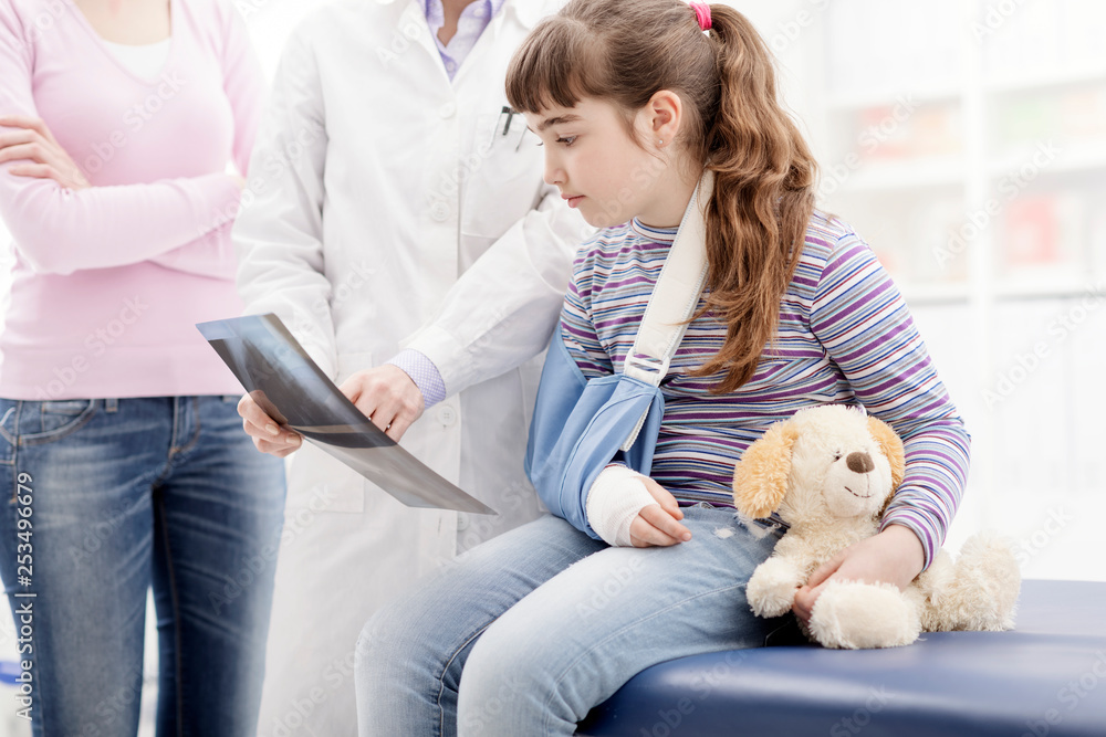 Doctor showing an x-ray to a young patient with broken arm Doctor showing an x-ray to a young patient with broken arm