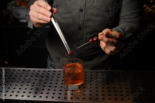 Bartender removing berries from the caretaker and put in into the cocktal glass photo