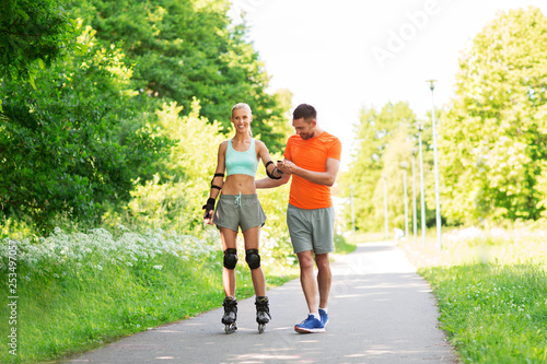 fitness, sport and healthy lifestyle concept - happy couple with roller skates riding outdoors in summer park