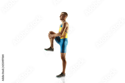 Young caucasian man warming up before run isolated on white studio background. One male runner or jogger. Silhouette of stretching athlete with shadows.