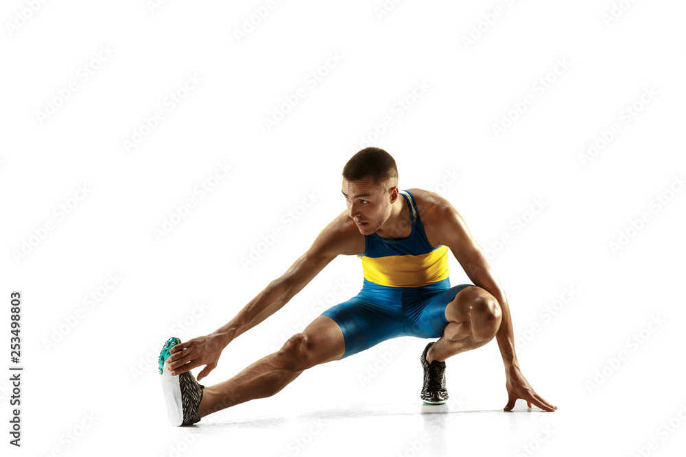 Young caucasian man warming up before run isolated on white studio background. One male runner or jogger. Silhouette of stretching athlete with shadows.