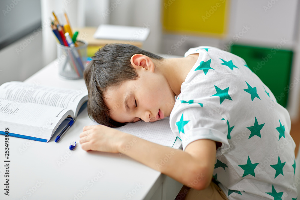education, childhood and school concept - tired student boy sleeping on table at home education, childhood and school concept - tired student boy sleeping on table at home