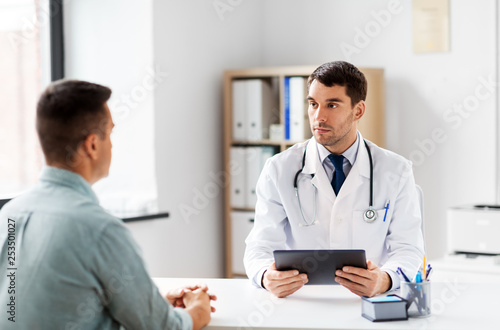 medicine, healthcare and technology concept - doctor with tablet pc computer and male patient talking at medical office in hospital