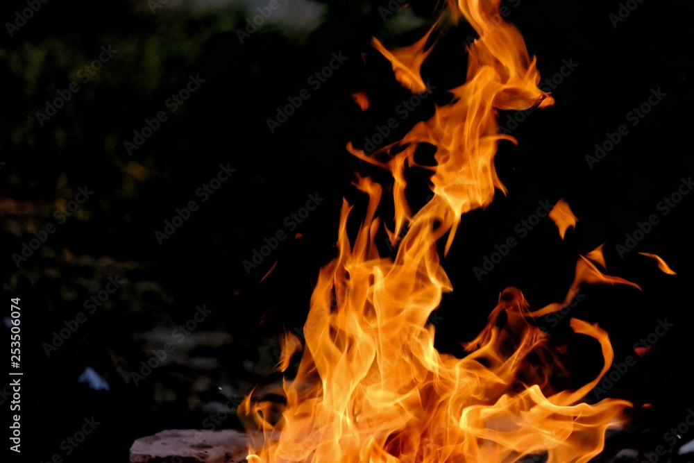Burning woods on the ground floor with a flame and fire sparking in outdoor place with dark background Burning woods on the ground floor with a flame and fire sparking in outdoor place with dark background