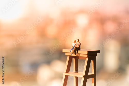 Miniature of a women and a man in love sitting on ladder with light copyspace, couple in love and pre-wedding background concept