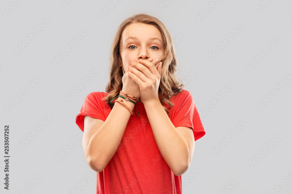 emotion, expression and people concept - speechless teenage girl with long hair in red t-shirt covering her mouth by hands over grey background